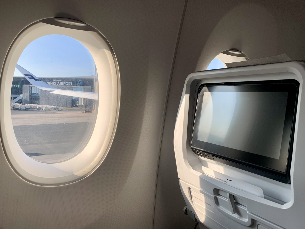 この写真は、飛行機の窓から見える景色を撮影したものですね。窓の外には「HELSINKI AIRPORT」という文字が見え、飛行機はヘルシンキ空港に停まっていることが分かります。また、機内のモニターや座席の様子も写っており、座席に座っている状態で撮影されたようです。この写真はフィンランドに関連した旅行の一部かもしれませんね。